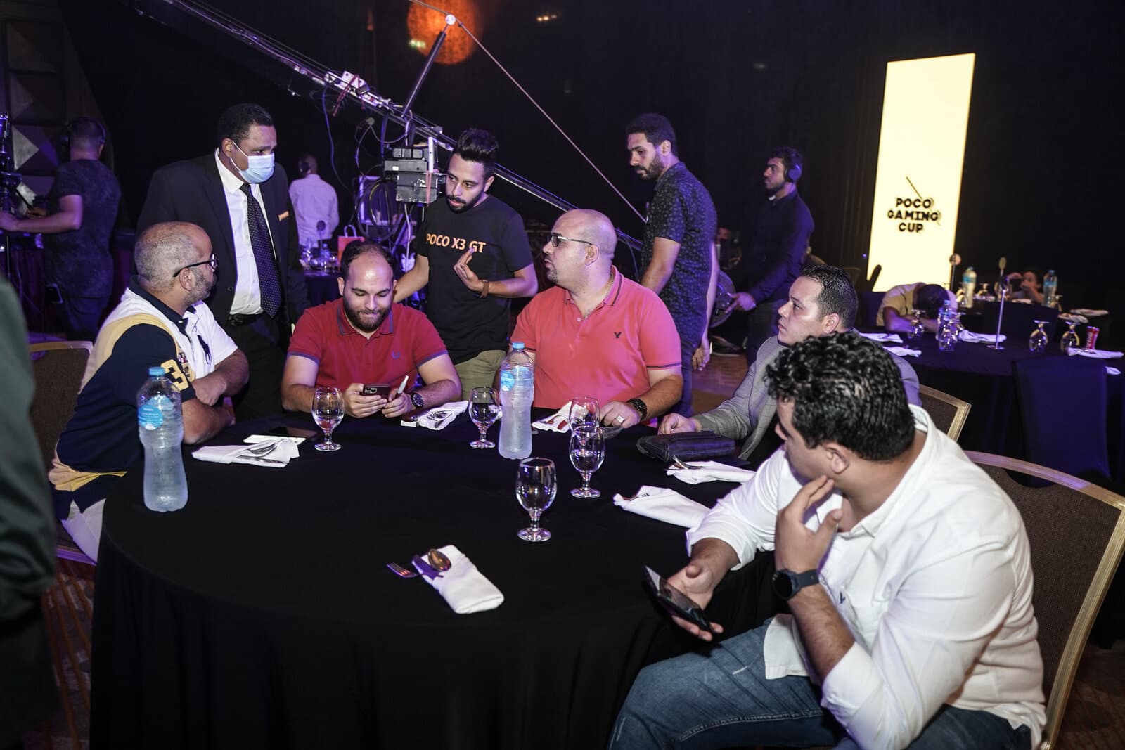 The event production table with a lit 'POCO Gaming Cup' sign visible in the background